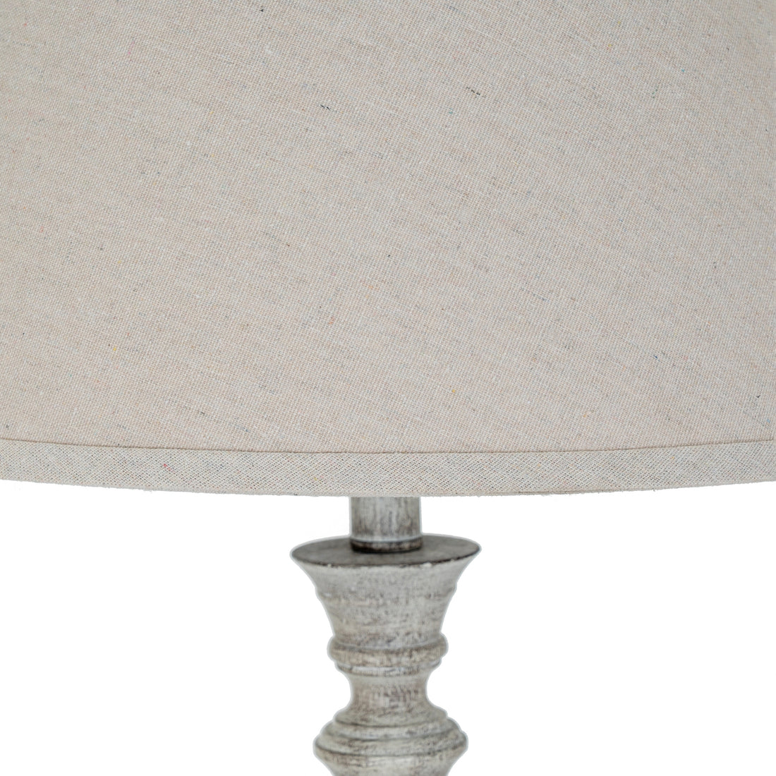 Close-up of a lamp with a textured base and fabric shade on a white background